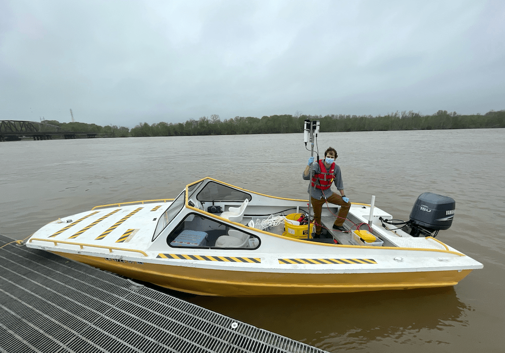A man holds a pole inside a white and yellow boat