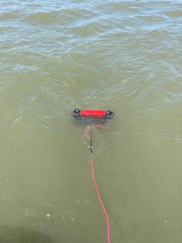 Instrument is connected submerged in water with red cable extending from it