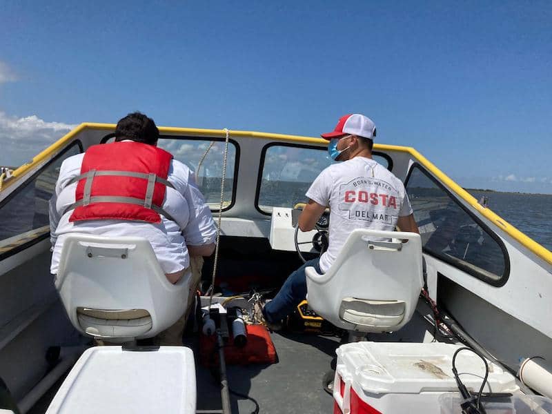 Two team members sit at the front of the boat