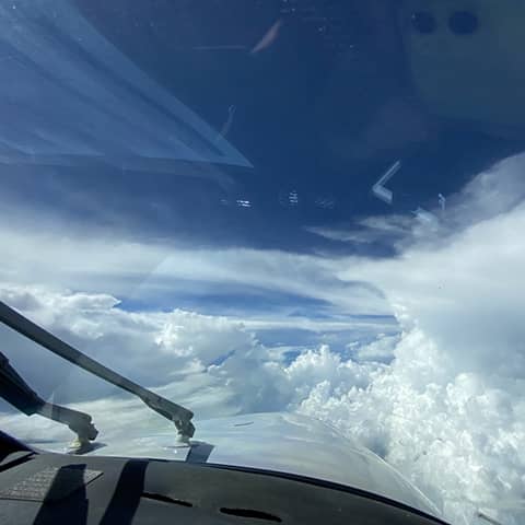 Large, cumulus clouds cover the sky out of the plane’s front window