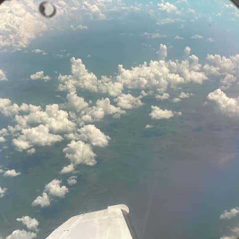 View out of the airplane window of scattered clouds over the delta