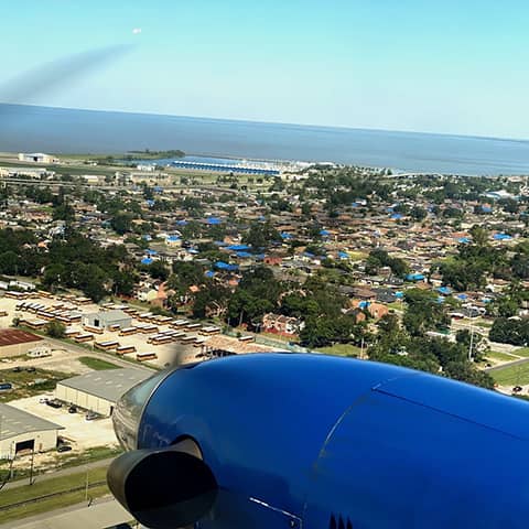 Low altitude view from aircraft of blue roofs scattered across the town