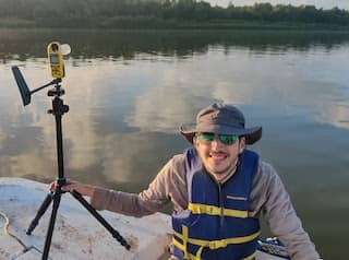 Michael holds an anemometer instrument on a boat