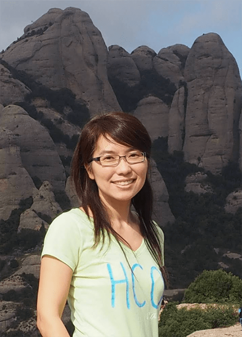 Yang smiles in the center with rock formations in the distance behind her